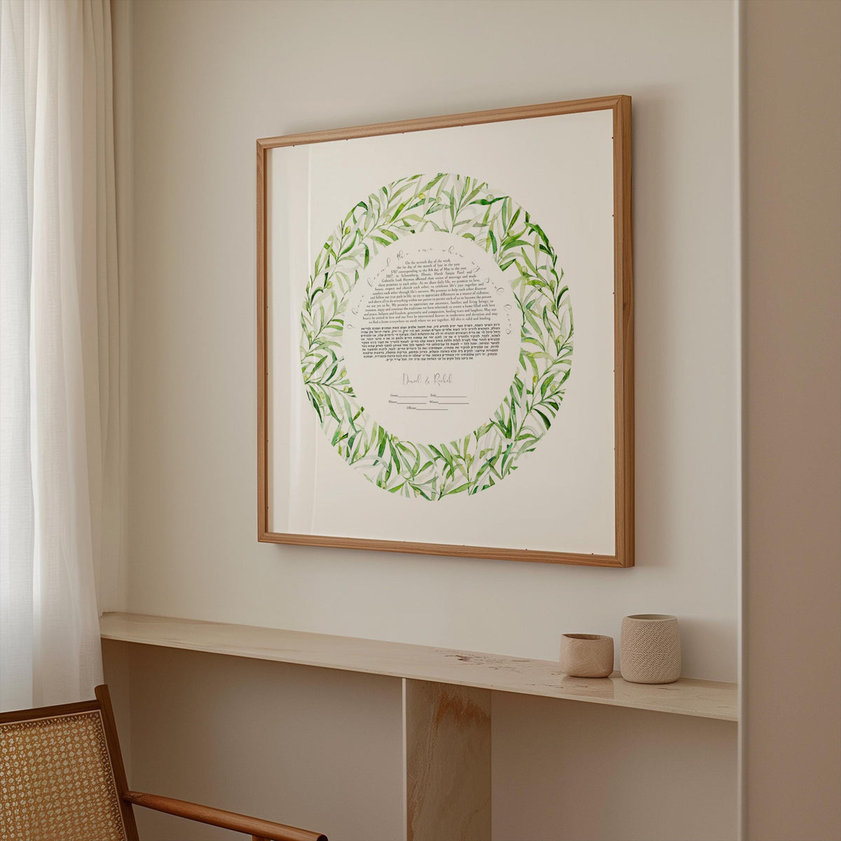 a framed artwork hanging on a wall, depicting a wreath with green leaves. The artwork is placed above a shelf with two small items on it.