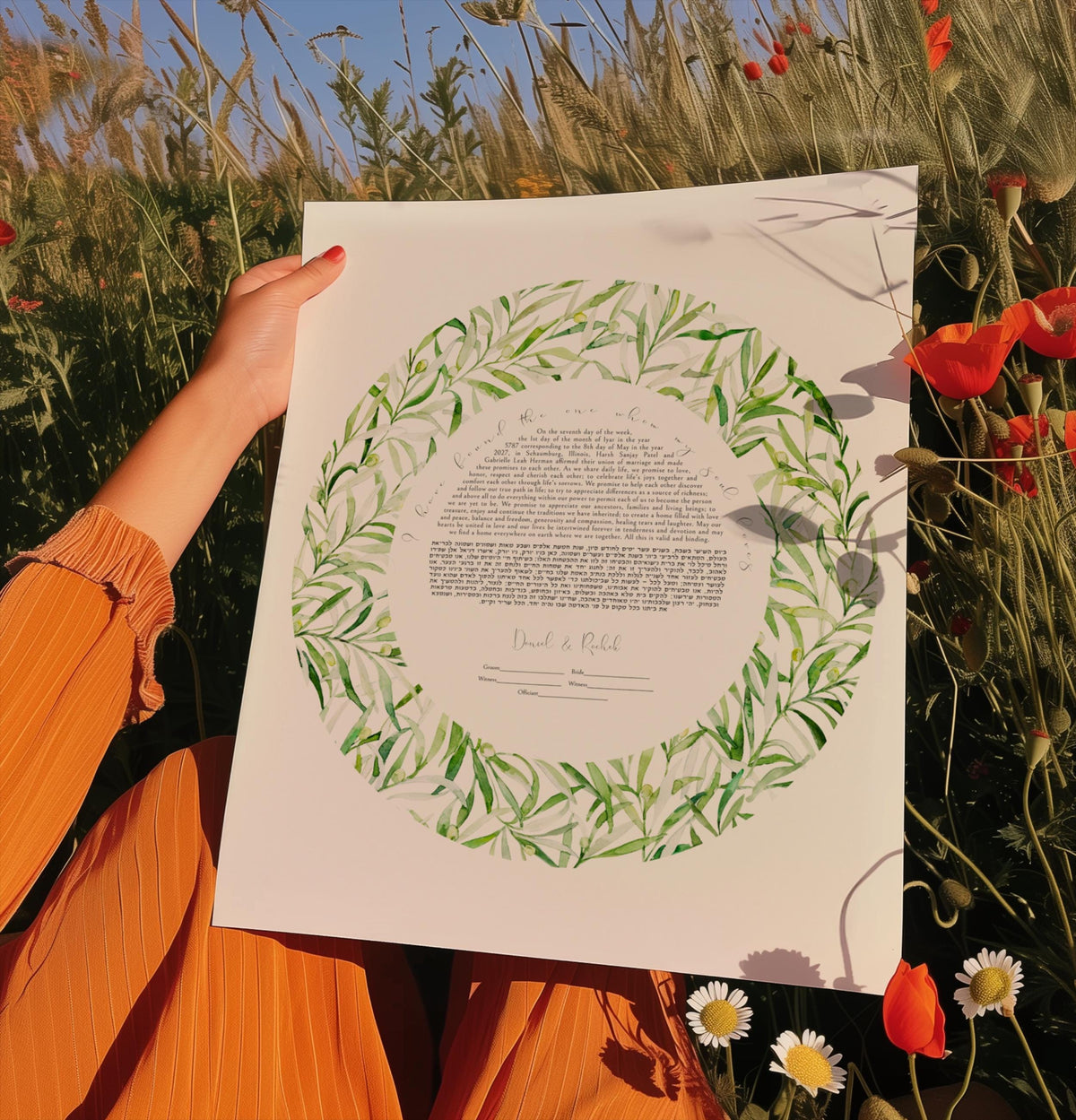 A person is holding a framed piece of paper with a wreath-like design on it, surrounded by a field of tall grass and flowers.